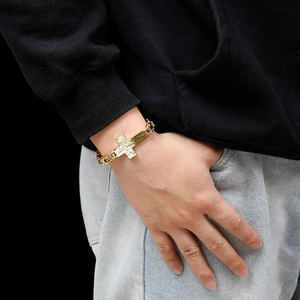 Men's retro gold titanium steel cross bracelet styled with casual streetwear on wrist