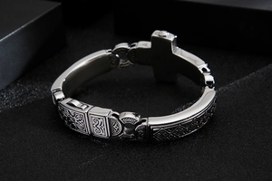 Close-up of vintage steel chain link bracelet featuring intricate cross engravings
