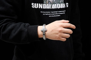 Macro detail of silver gothic cross bracelet with vintage punk steel links and metal texture
