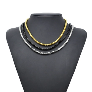 Detailed view of three-color box chains in gold, black and silver on a neck mannequin