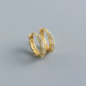 Macro view of gold snake scale earrings with geometric segments and pavé crystals