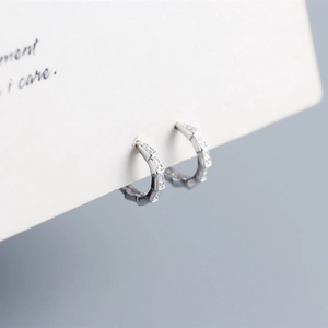 Macro detail of S925 sterling silver hoop earrings with textured zircon stones