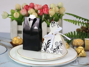 Macro detail of bride gown and groom tuxedo wedding favor boxes with satin ribbon