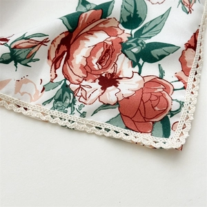 Floral cotton headscarf with red roses and cream crochet lace trim in a close-up view