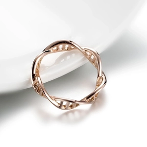 Macro shot of rose gold DNA double helix ring resting on white ceramic surface