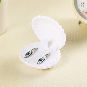 White shell jewelry box detail showing velvet interior with blue crystal earrings