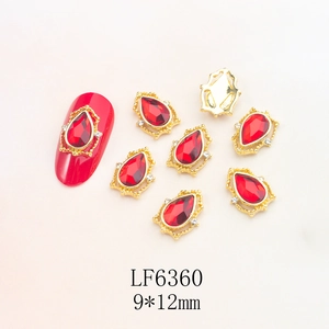Macro detail of red teardrop nail jewelry with gold lace setting and 9x12mm dimensions