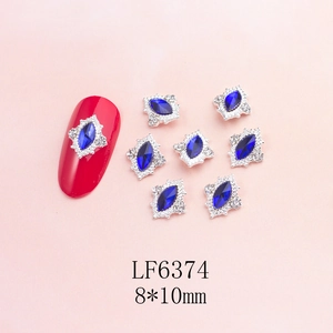 Macro detail of blue marquise rhinestone nail charm with silver frame on red fake nail