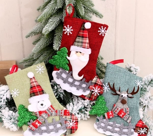 Three linen Christmas stockings featuring Santa, bear, and reindeer with plaid details