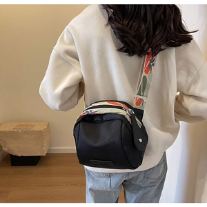 Detail of black nylon crossbody bag featuring a colorful patterned wide shoulder strap