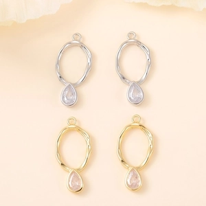 Macro detail of gold and silver dollar sign pendants with teardrop zircon stones
