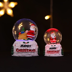 Détail d'une boule à neige de Noël lumineuse avec Père Noël et socle blanc
