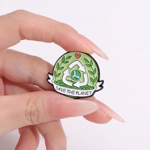 Green Save the Planet enamel pin with recycle symbol and earth on light pink backdrop