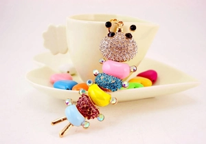 Close-up of a colorful rhinestone caterpillar keychain displayed in a white ceramic dish