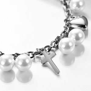 Detail of silver double-chain bracelet with white pearls, cross and heart charms