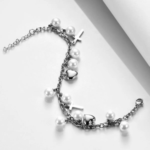 Detail of silver stainless steel bracelet with white pearls, hearts and cross charms