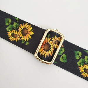 Dettaglio della tracolla nera con motivo a girasole e fibbia dorata regolabile