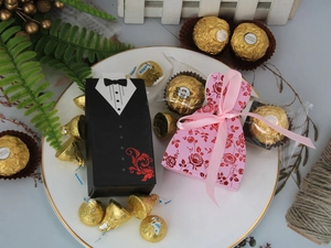 Detail von Hochzeits-Gastgeschenkboxen im Smoking- und Kleid-Stil auf goldenem Teller