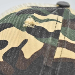 Gros plan sur la casquette de baseball camouflage avec détails usés et texture coton