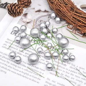 Silver decorative Christmas berry picks on book pages with pine cones and branches
