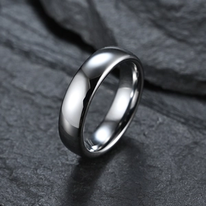 Polished silver tungsten carbide ring with a smooth curved surface on a grey rock background