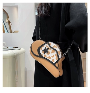 Detail of cowboy hat-shaped crossbody bag with cow print decor and silver chain