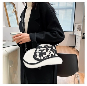 Detail of cowboy hat shaped shoulder bag featuring cow print and star accent