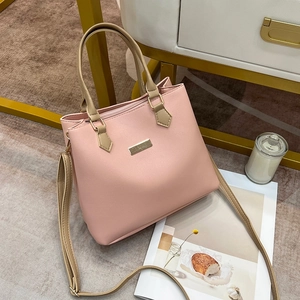 Close-up of pink tote bag with golden handles placed near a candle and magazine