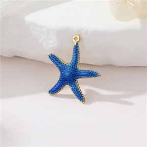 Macro shot of a dark blue starfish charm with gold-plated edges and granular enamel finish