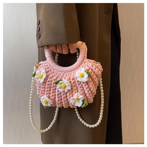 Close-up of pink handmade shell bag with daisy decor and elegant pearl handle