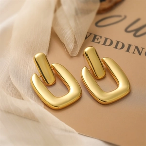 Detailed view of geometric 18K gold earrings with high-polish finish on soft fabric