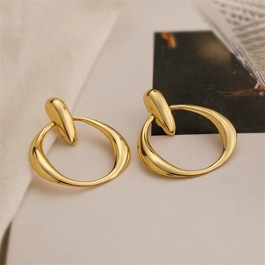 Macro detail of high-polished 18K gold plated teardrop tassel earrings with a metallic finish