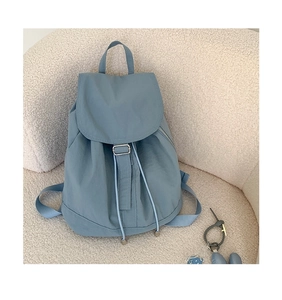 Dettaglio dello zaino in nylon blu con coulisse su sfondo bianco testurizzato con patta