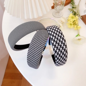 Close-up of three houndstooth fabric headbands with wide padding on a warm aesthetic background