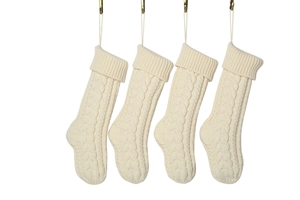 Detail of four cream white chunky knit Christmas stockings with cable pattern textures