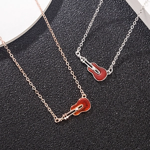 Elegant violin necklace in rose gold and silver with red guitar pendant on black surface