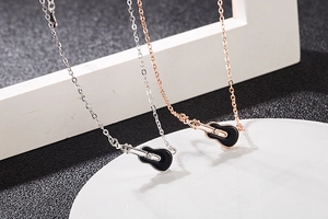 Detailed view of silver and rose gold guitar necklaces with black enamel and zircons