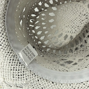 Dettaglio dell'interno del cappello in paglia di carta con trama e etichetta di cura