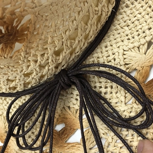 Vista macro del cappello di paglia intrecciato beige con dettaglio di corda marrone