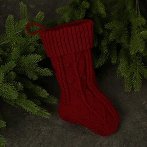 Classic red cable-knit Christmas stocking with hanging loop on a festive background