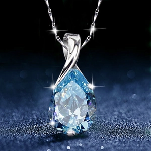 Silver necklace featuring a sparkling blue teardrop crystal pendant on a dark background