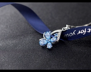 Macro shot of a silver four-leaf clover pendant with marquise blue stones and crystals