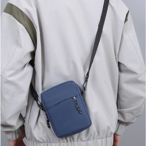 Minimalist blue canvas crossbody bag with adjustable strap and front pocket detail