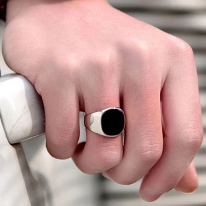 Polished silver stainless steel ring with a large oval black gemstone on a finger