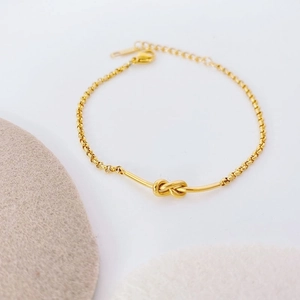 Detail of 18k gold knot bracelet with adjustable rolo chain and lobster clasp