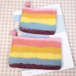 Rainbow striped wool felt coin purse with pink pompom zipper on a checkered tablecloth