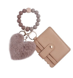 Close-up of beige leather card holder with heart plush ball and silicone bead keychain