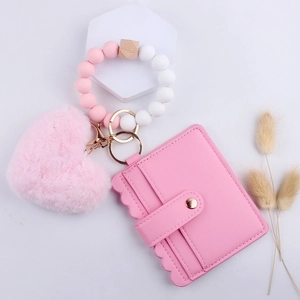 Pink heart plush keychain with beaded silicone wristband and wallet on display
