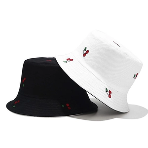 Detailed close-up showing embroidered cherry patterns on black and white cotton bucket hats