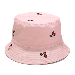 Detailed view of light pink bucket hat featuring delicate red cherry embroidery